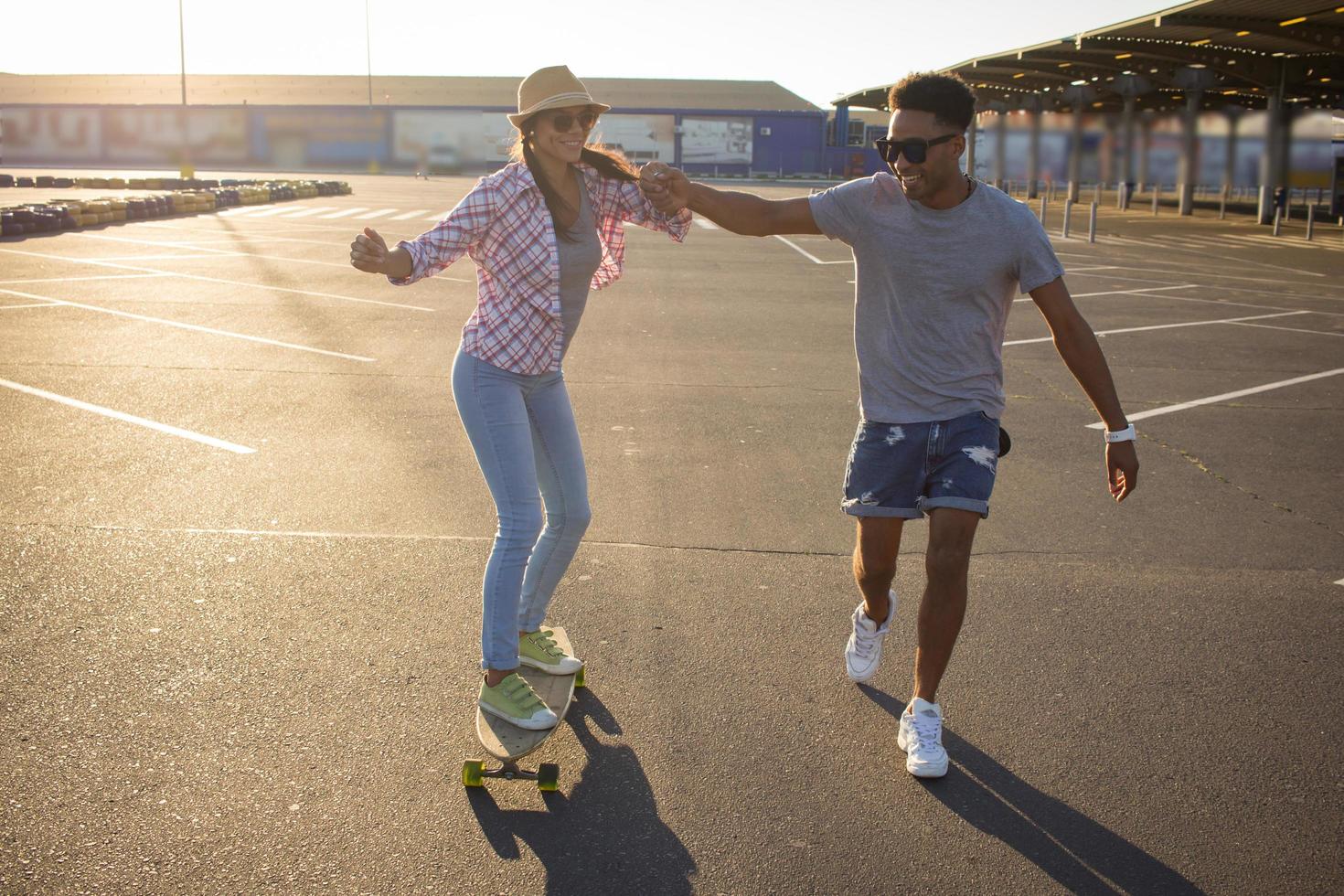 gelukkig jong stel skateboard rijden tijdens zonsopgang foto