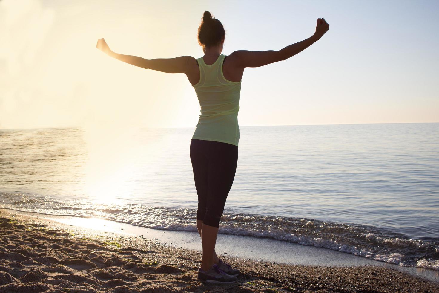 jonge professionele turnstervrouw danst op het strand, trainingsoefeningen met coole junps, zonsopgang op zee of oceaanachtergrond foto