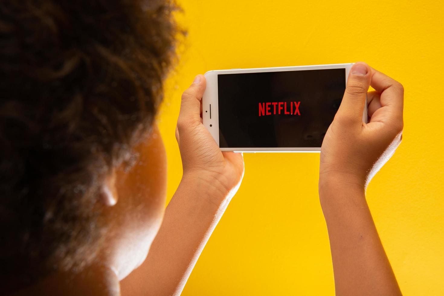 ribeirao preto, sao paulo brazilië circa november 2019 opent netflix-toepassingspictogram op iphone 8 plus jongen rustend met haar mobiele telefoon in haar handen en het netflix-logo op het scherm. foto