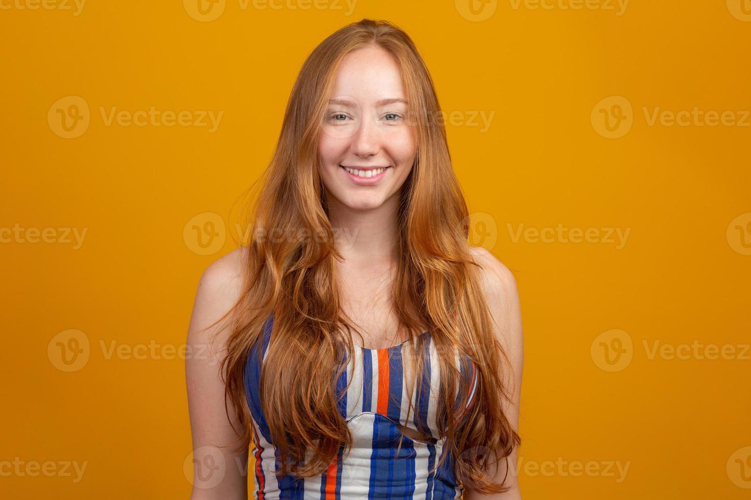 portret van mooie vrolijke roodharige meisje met vliegende haren lachend lachen camera kijken over gele achtergrond. foto