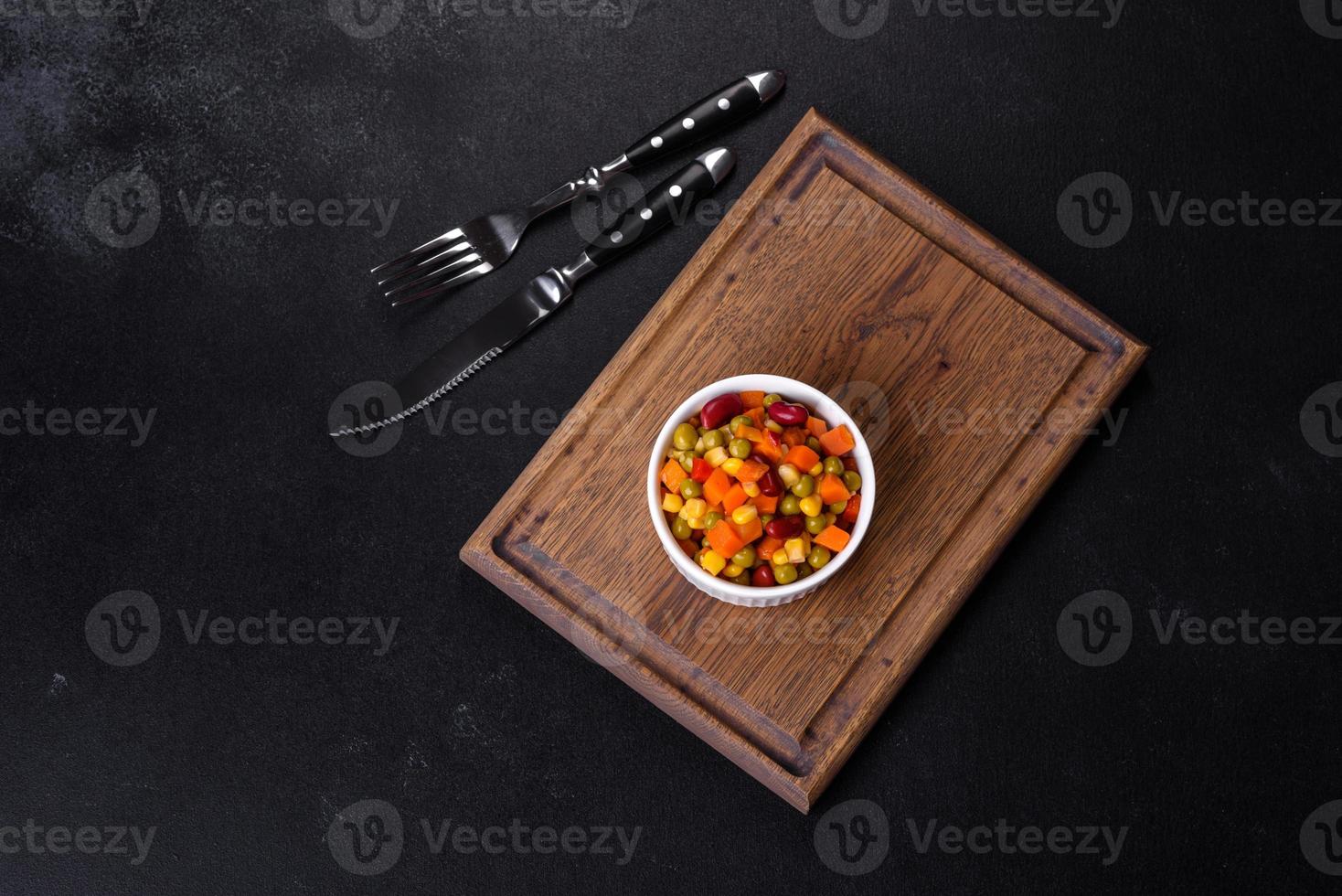 een mengsel van gehakte groenten paprika, maïs, erwten in wit bord foto