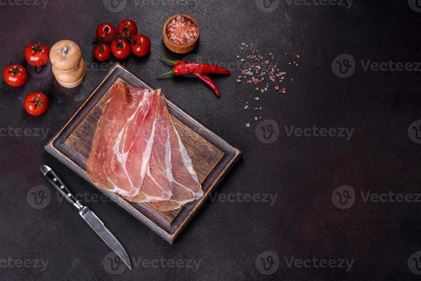 Italiaanse prosciutto crudo of Spaanse jamon op een donkere snijplank foto
