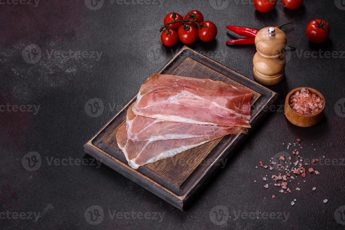 Italiaanse prosciutto crudo of Spaanse jamon op een donkere snijplank foto