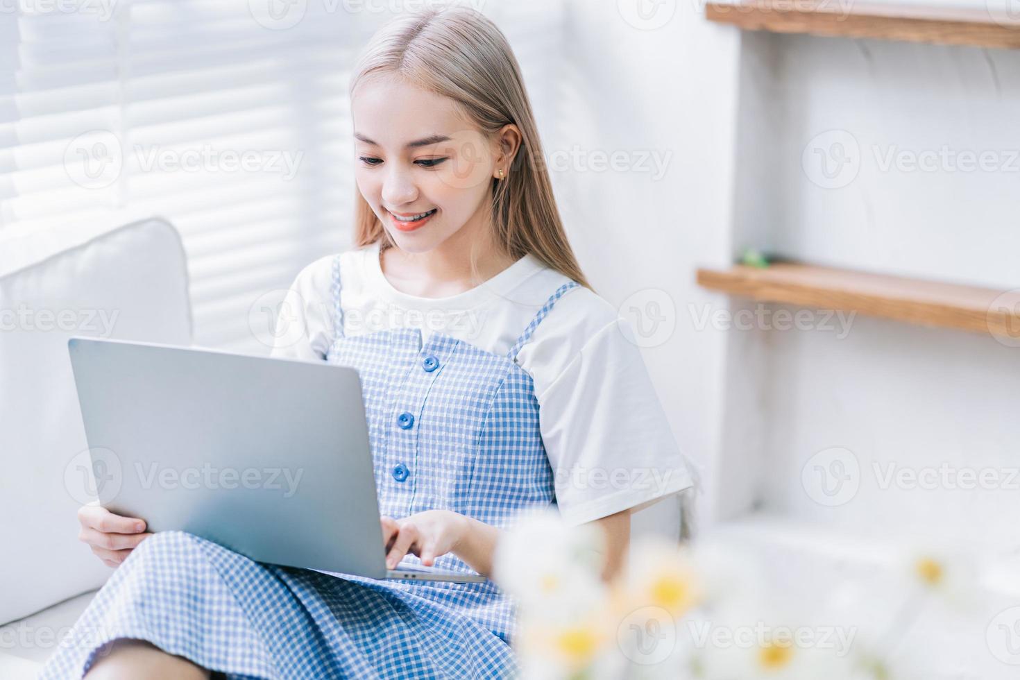 jong Aziatisch meisje dat laptop thuis met behulp van foto