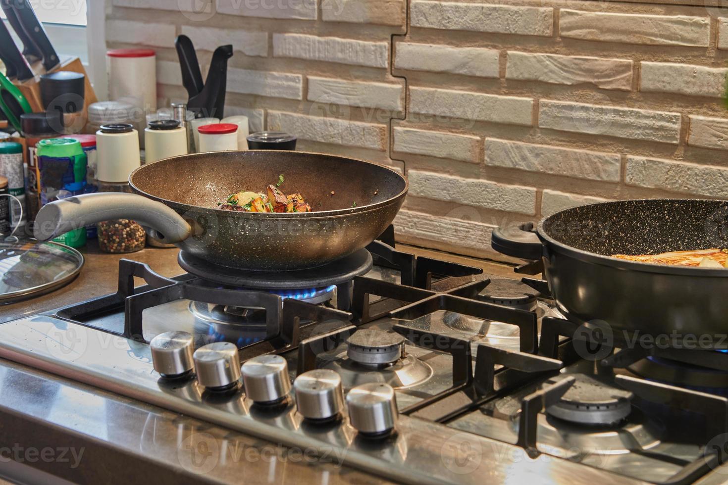 koekenpannen met gebakken aardappelen, kastanjes, peterselie, Parmezaanse kaas op gasfornuis in de keuken. stap voor stap recept foto