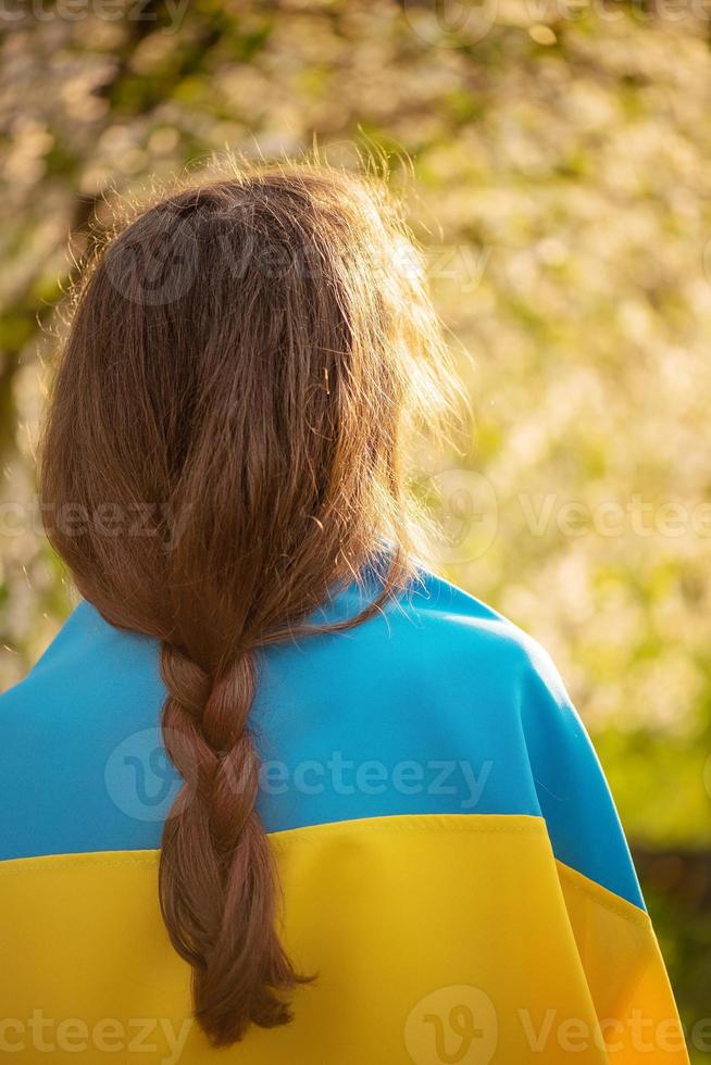 gele en blauwe stof op het meisje. het meisje staat achter de camera met de Oekraïense vlag. foto