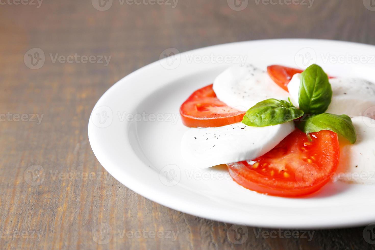 caprese salade met mozarella kaas, tomaten en basilicum op plaat foto