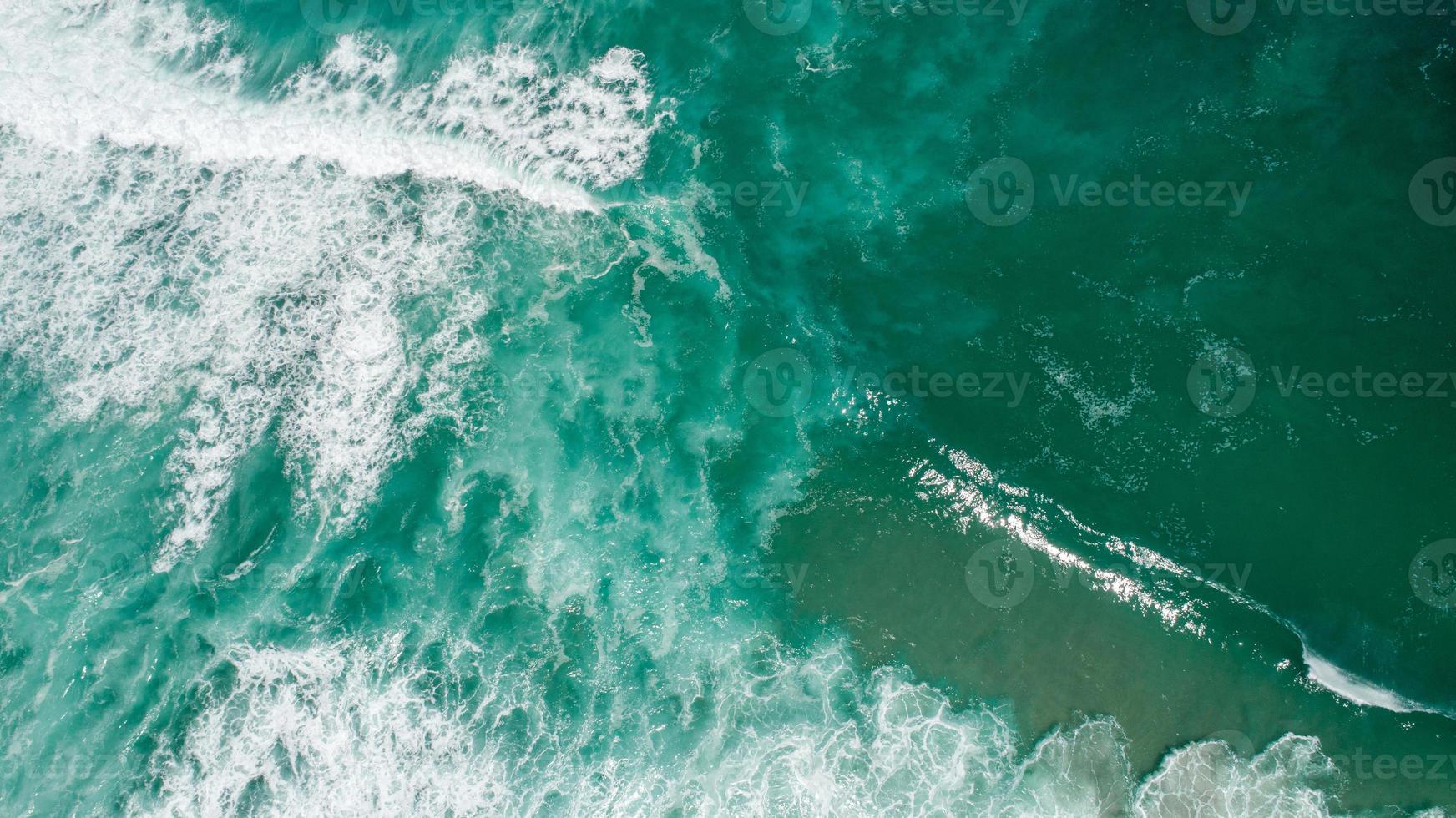 bovenaanzicht textuur golven, schuimend en spetterend in de oceaan, zonnige dag foto