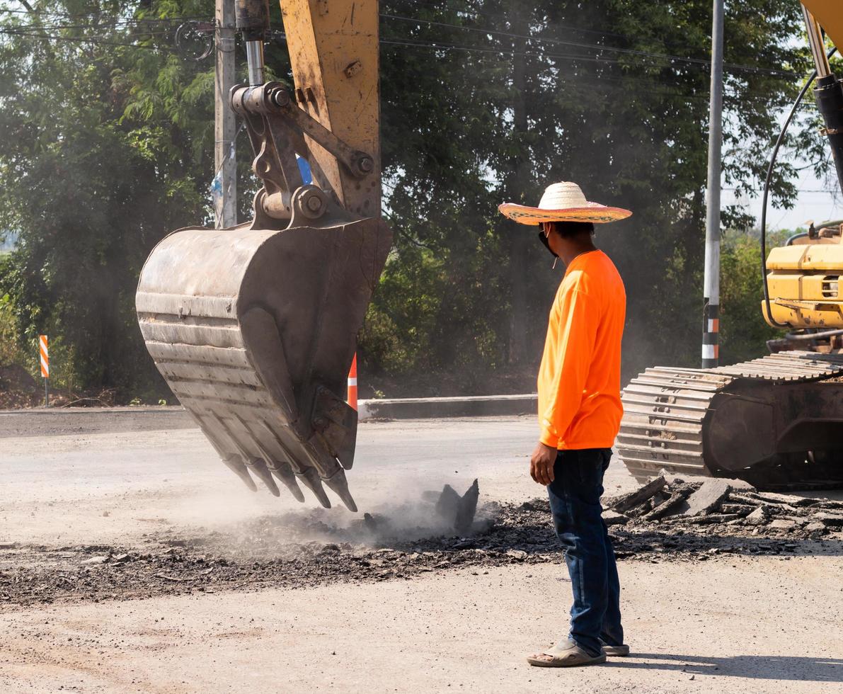 arbeiders met een graafmachine om de weg te slopen. foto