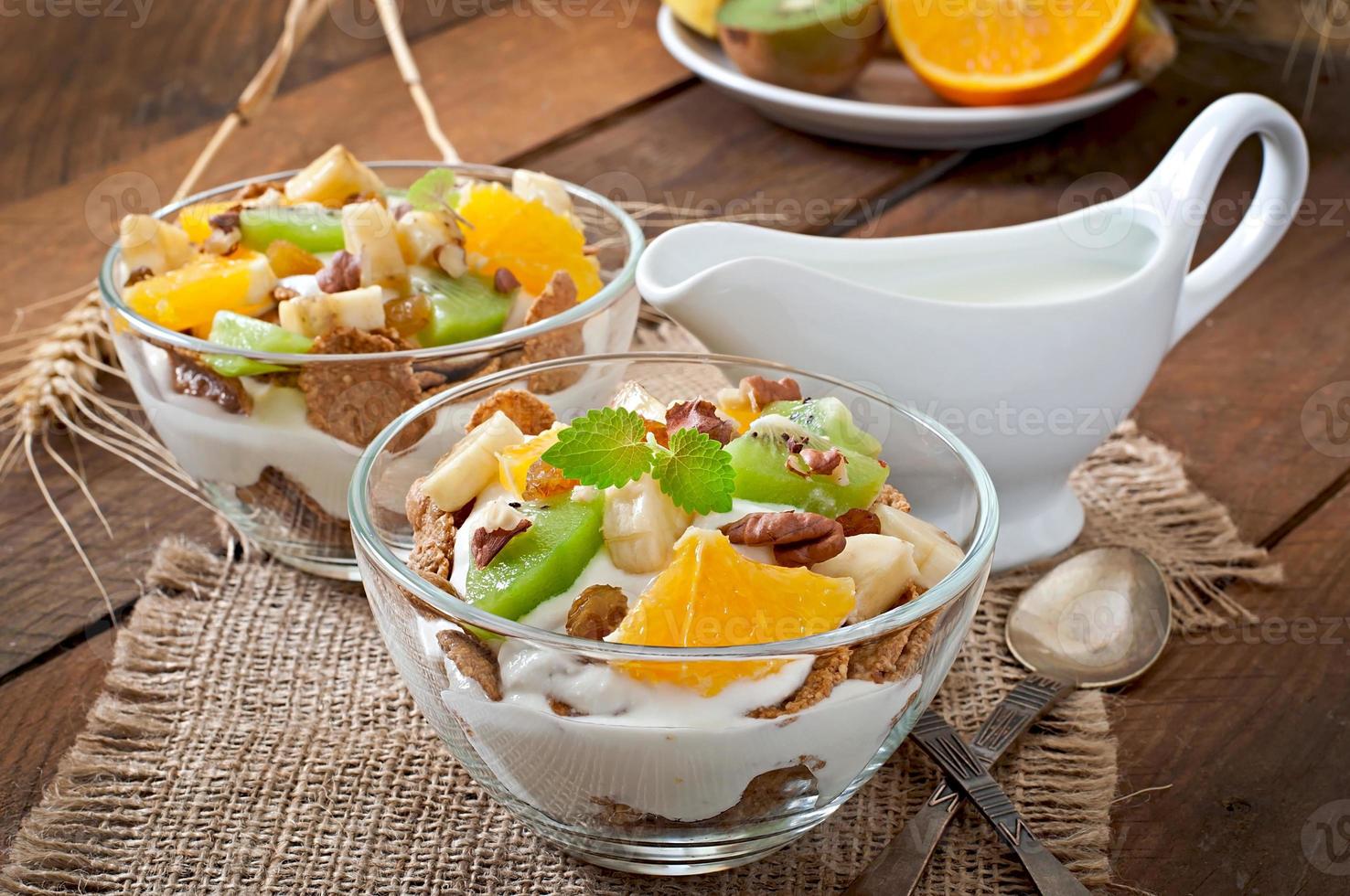 gezond dessert met muesli en fruit in een glazen kom op tafel foto