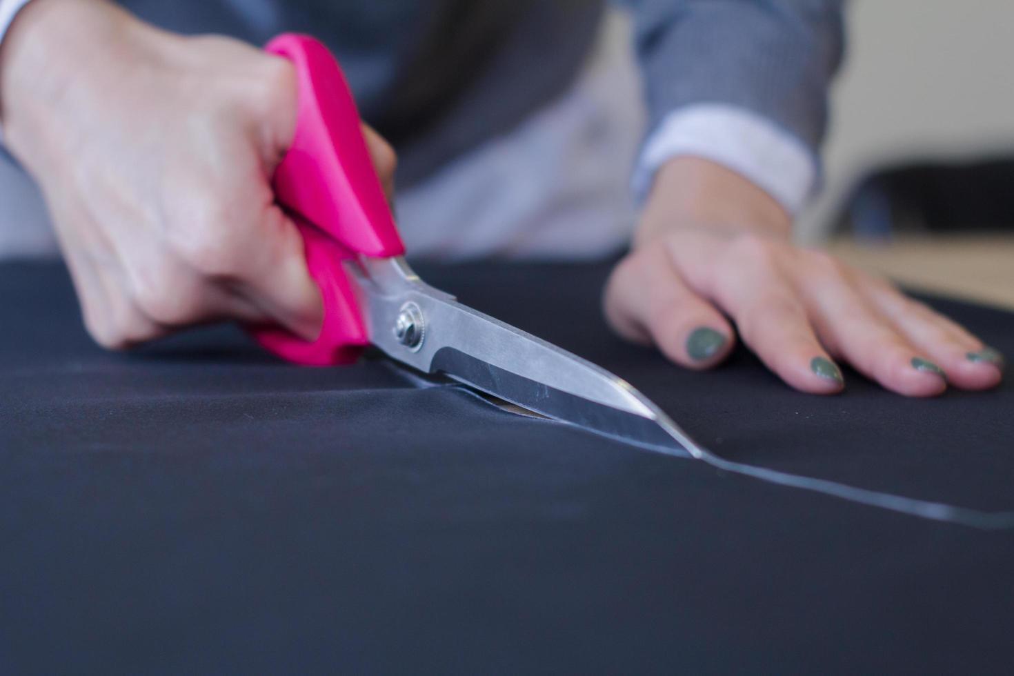 naaister aan het werk aan tafel, kleermaker vrouw werk in studio met kleding foto