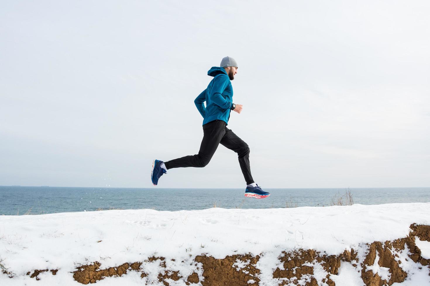 jonge mannelijke hardloper die in de winter buiten traint, man rent in de sneeuw foto