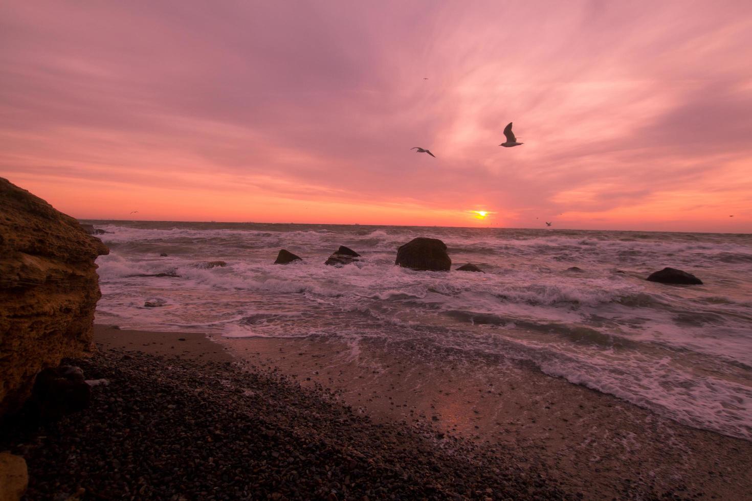 prachtig zeelandschap in zonsopgang, kleurrijke roze en oranje lucht en storm in de zee. foto