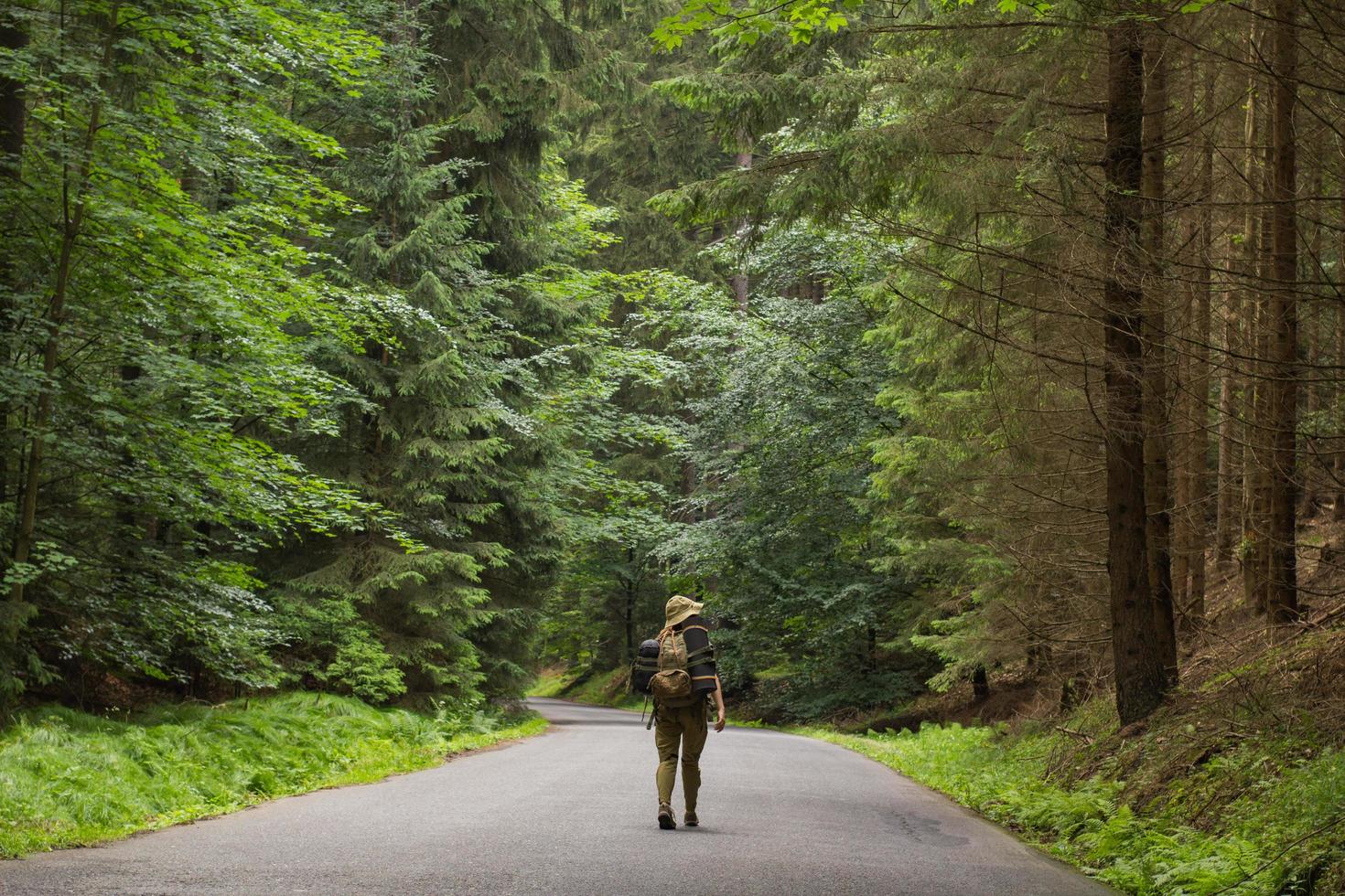jonge vrouw wandelaar wandelen op smalle weg door zomer groen bos foto