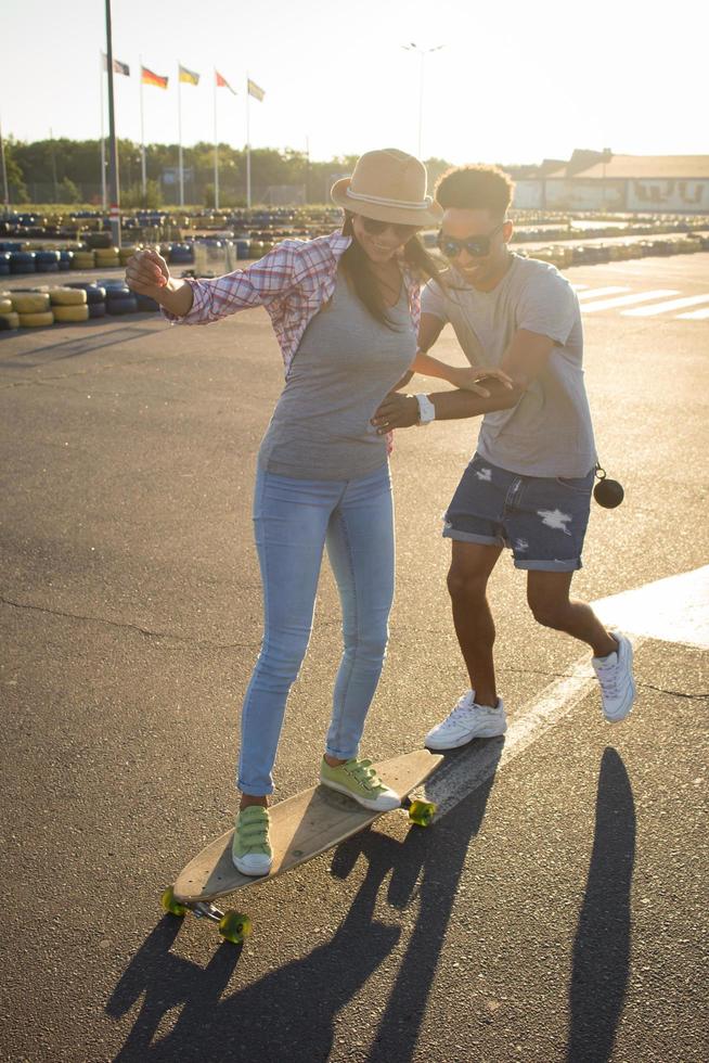 gelukkig jong stel skateboard rijden tijdens zonsopgang foto