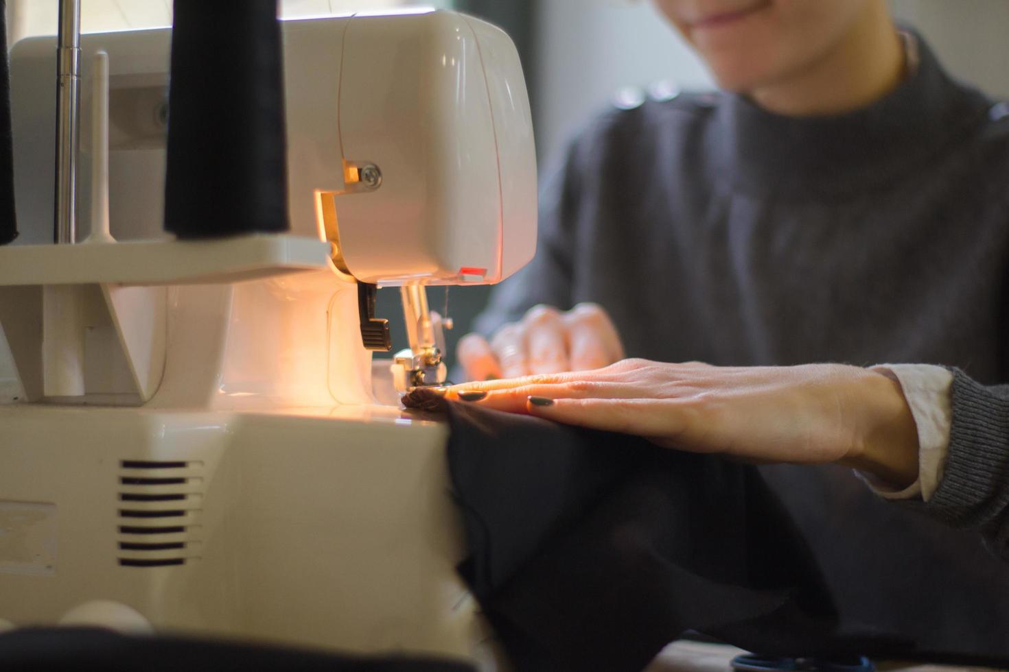 naaister aan het werk aan tafel, kleermaker vrouw werk in studio met kleding foto