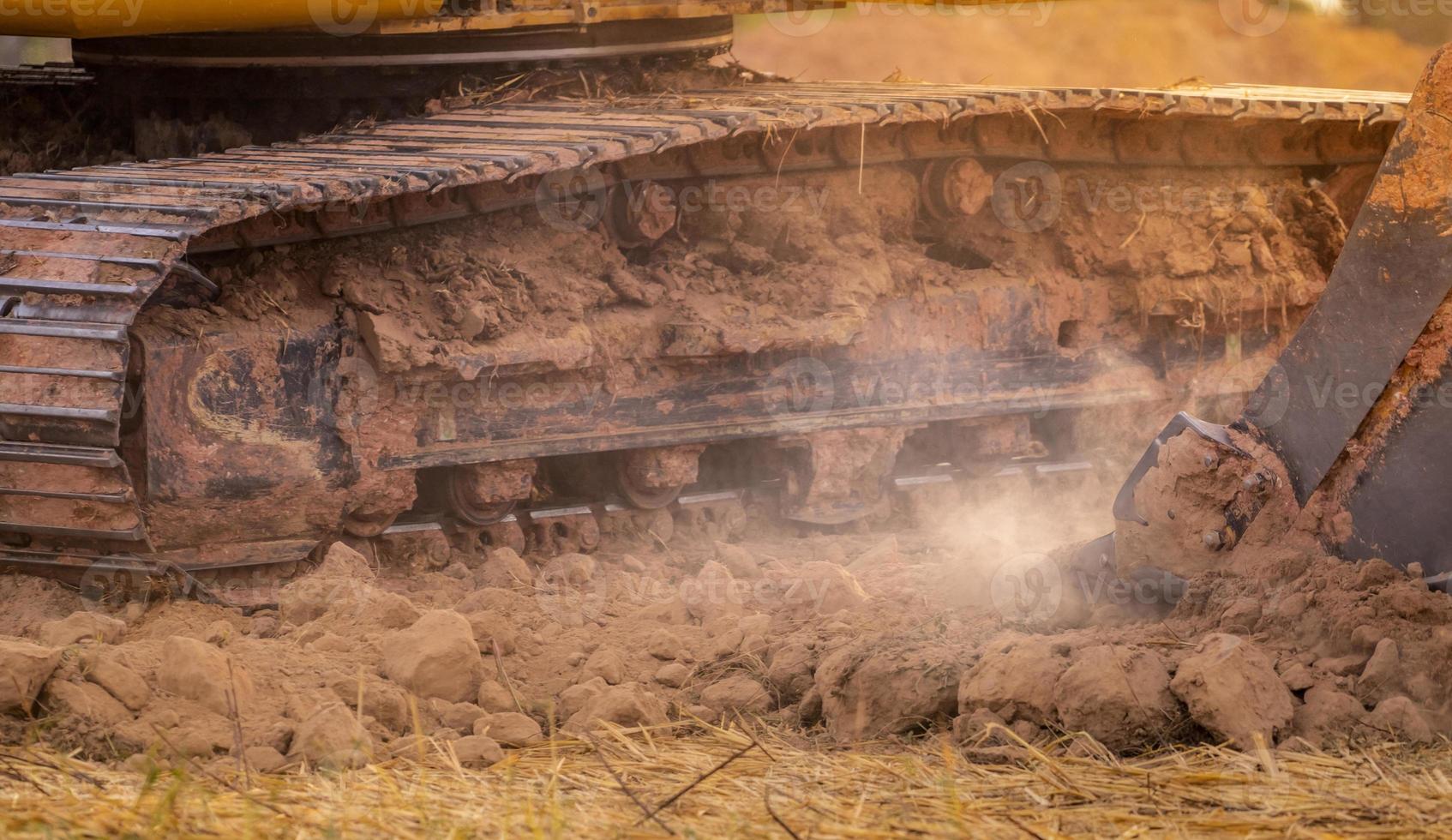 backhoe werken door grond te graven op de bouwplaats. emmertanden van backhoe-gravende grond. rupsgraafmachine die op grond graaft. graafmachine. grondverzetmachine. graaf voertuig. trackpad. foto