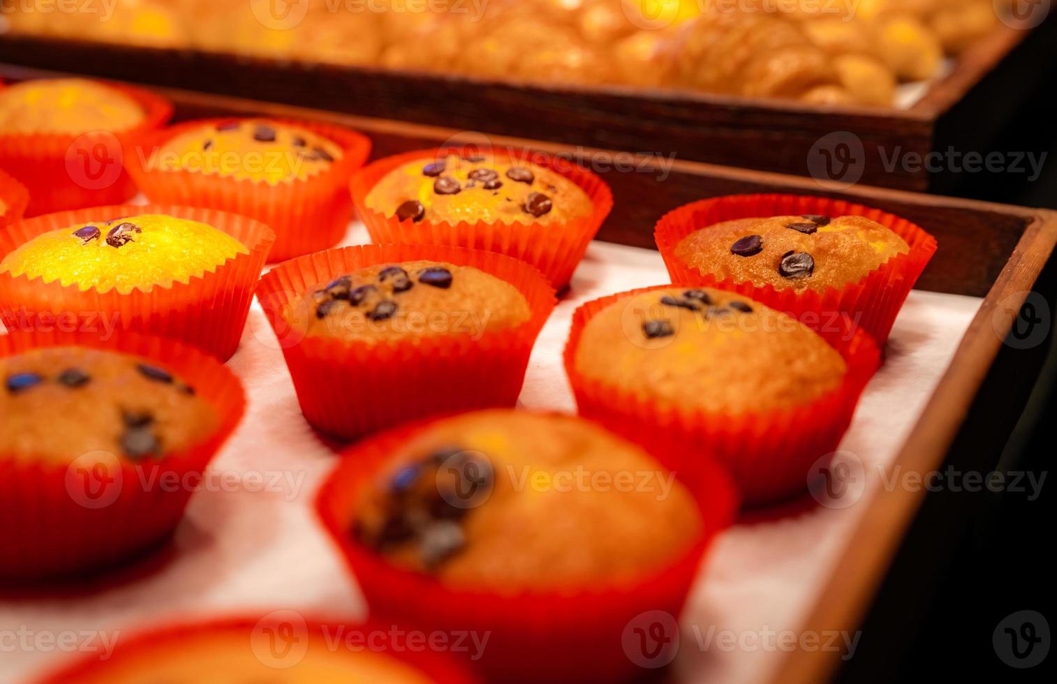 bakkerij in bruin houten dienblad in bakkerijwinkel. vers gebakken gebak product. zoet brood display op teller. koolhydraten eten. tussendoortje voor ontbijt of lunch. bakkerij detailhandel. zelfgemaakte bakkerij bedrijf. foto