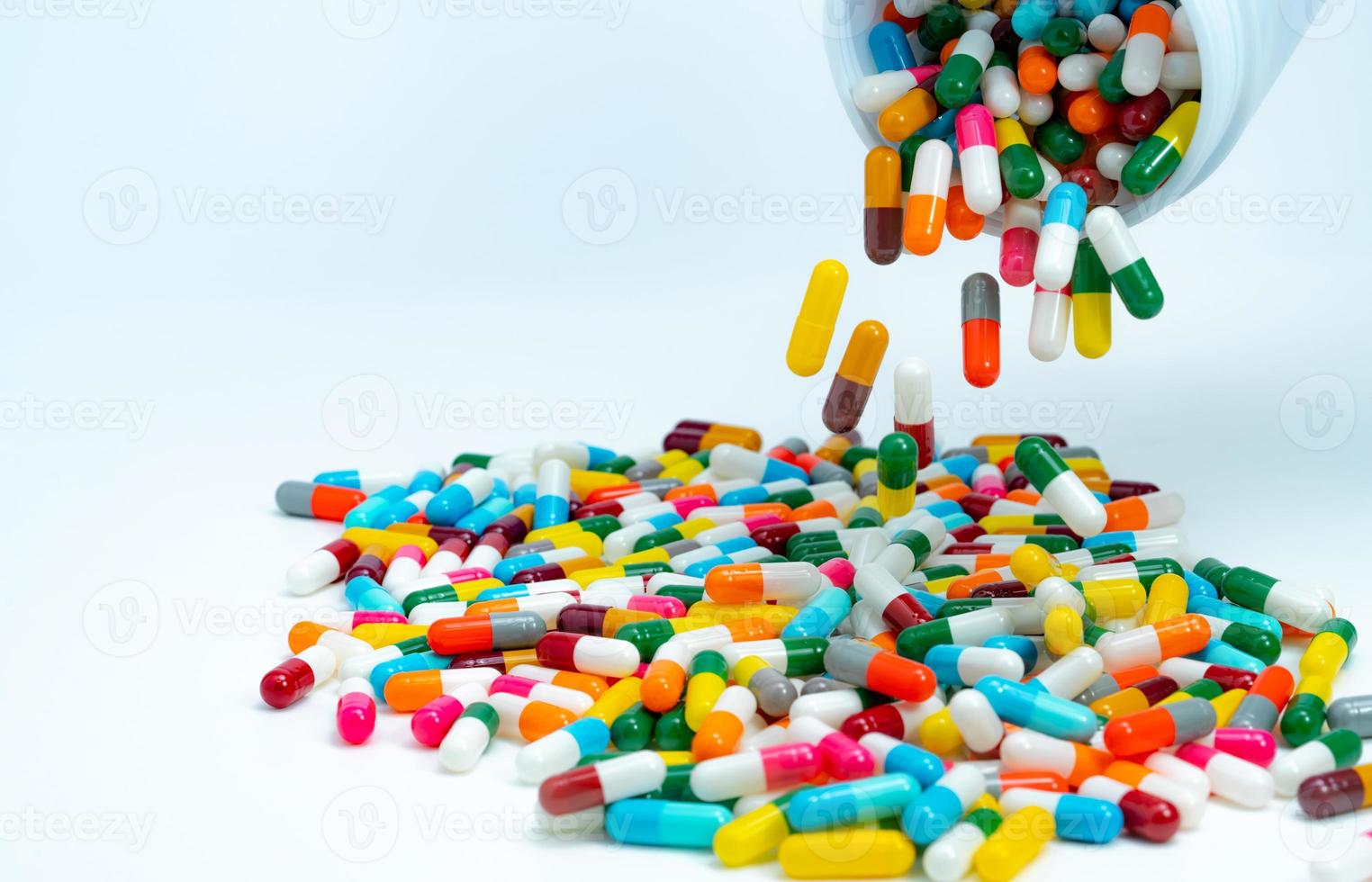 capsulepillen van plastic medicijnfles naar witte tafel gieten. stapel kleurrijke capsulepillen. farmaceutische industrie. gezondheidszorg en geneeskunde achtergrond. farmaceutisch concept. interacties tussen geneesmiddelen. foto