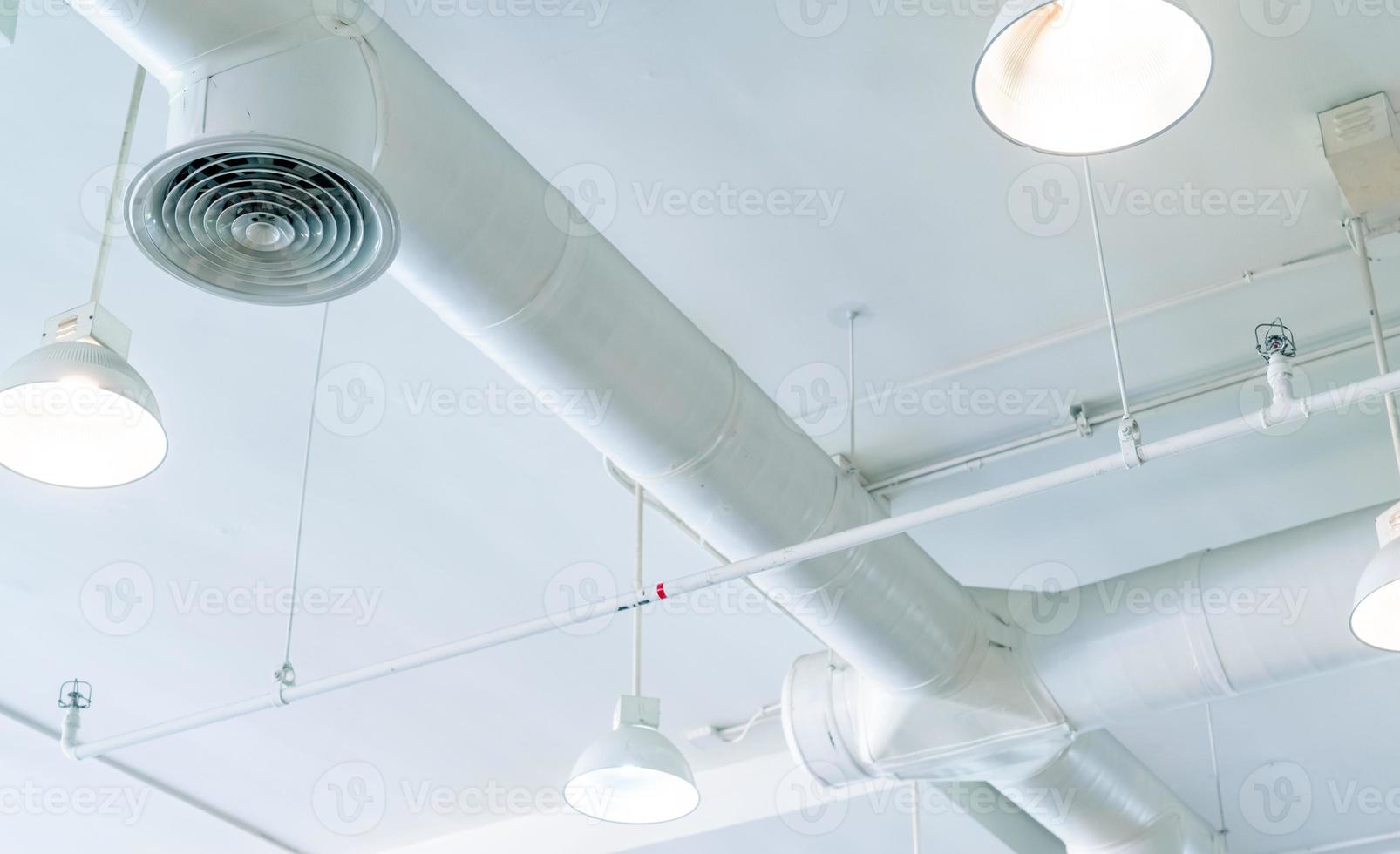 luchtkanaal, airconditionerpijp en brandsprinklersysteem op witte plafondmuur. luchtstroom en ventilatiesysteem. interieur bouwen. plafondlamp licht met geopend licht. interieur architectuurconcept. foto