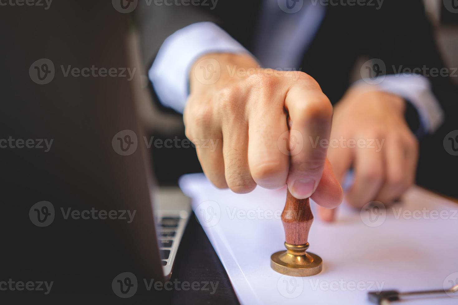 close-up van iemands hand stempelen met goedgekeurde stempel op goedkeuring certificaat document openbaar papier aan bureau, notaris of zakenmensen werken vanuit huis, geïsoleerd voor coronavirus covid-19 bescherming foto