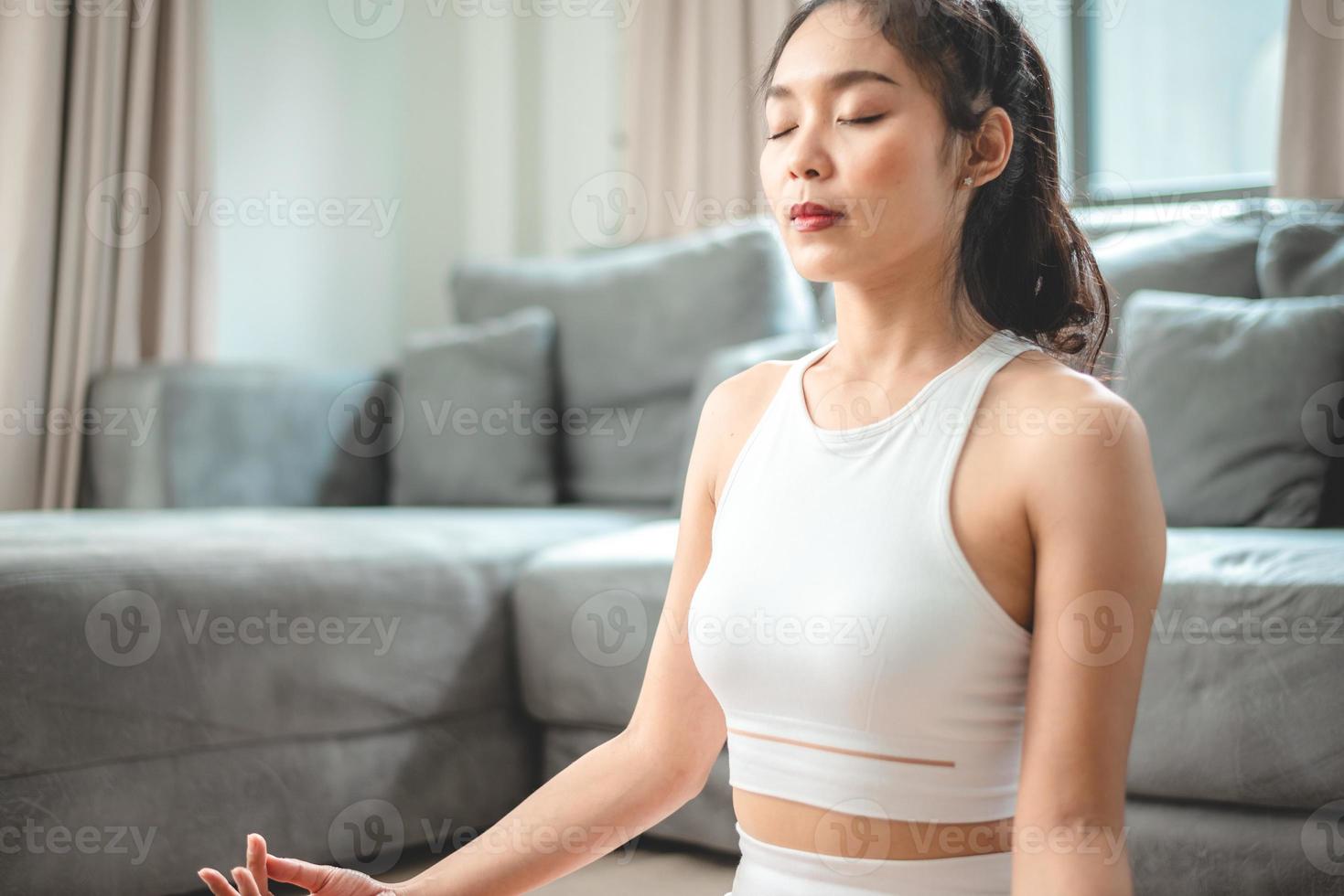 jonge aziatische vrouw oefent door yoga thuis sportschool, gezonde vrouwelijke levensstijl met fitness sporttraining thuis, meisje doet lichaamsactieve lichaamsbeweging binnenhuiskamer, ontspanning en welzijn foto