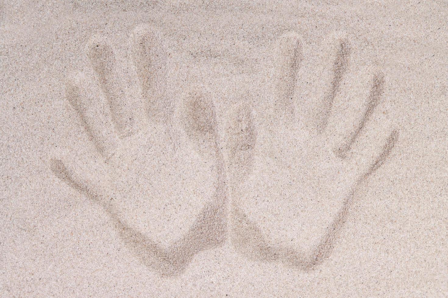 de afdruk van twee menselijke palmen op het zand van bovenaf foto