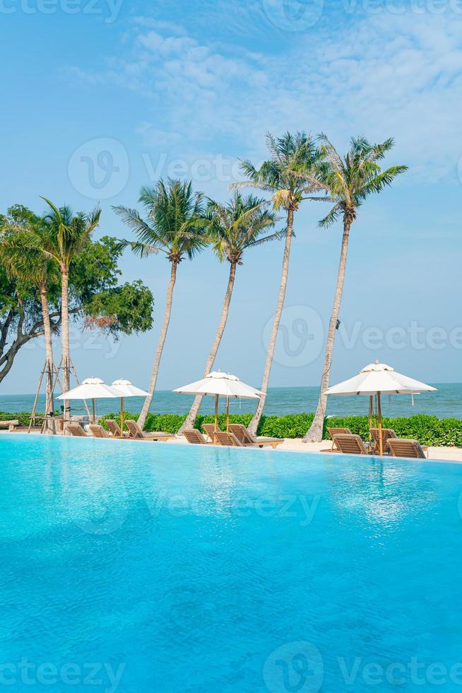 parasol met bed zwembad rond zwembad met oceaan zee achtergrond foto