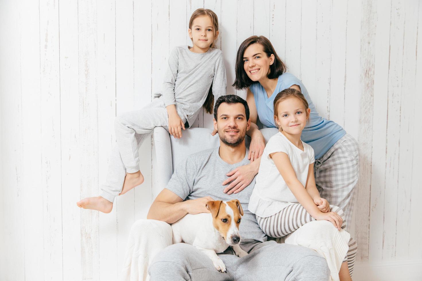 vriendelijk gezin van vier leden vrolijke europese brunette vrouw, haar man, twee dochters en favoriete huisdier, hebben goede relaties, steunen elkaar. aanhankelijke ouders met kinderen foto