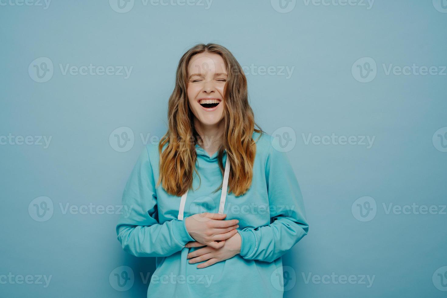 lachende vrouw met handen op buik poseren in studio foto