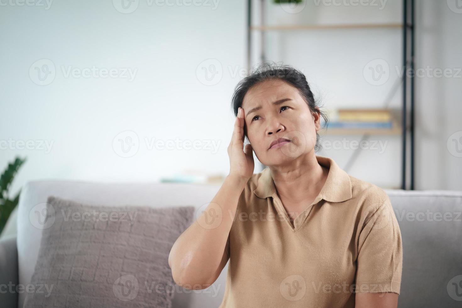 uitgeput moe depressief gestrest doordachte volwassen senior vrouw die lijdt aan hoofdpijn, hersenziekten, mentale problemen, het concept van alzheimer. foto