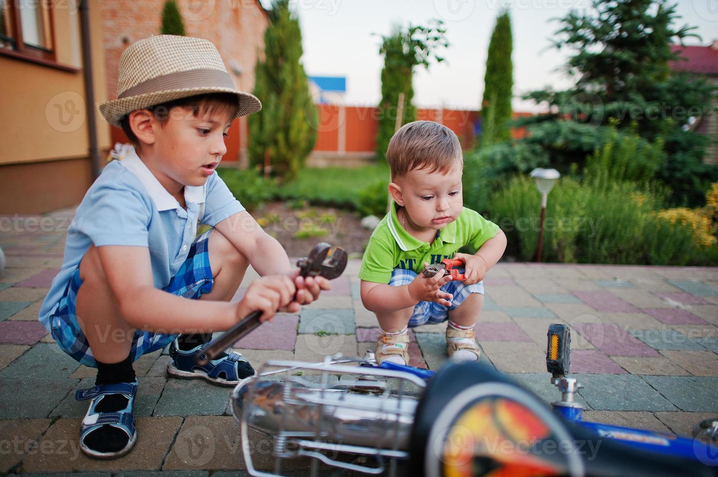 twee broers repareren fiets. kleine monteurs werken met de fiets. foto