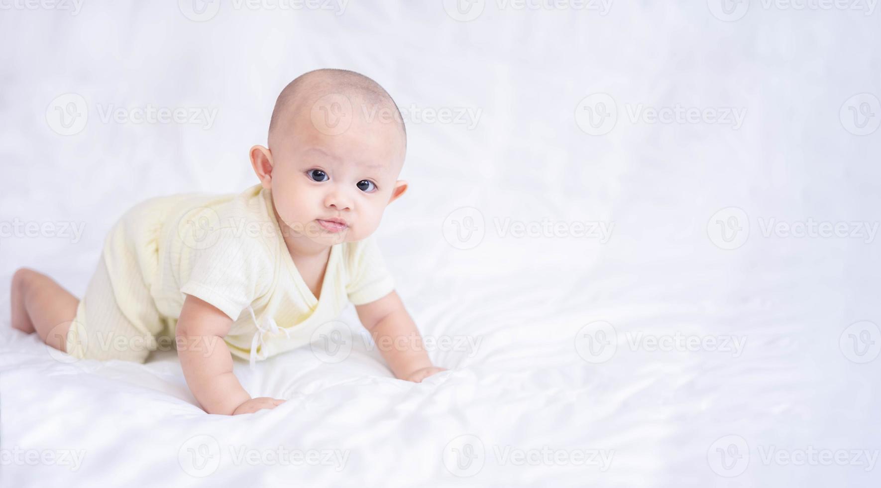 gelukkige familie, schattige Aziatische pasgeboren babyjongen liggend spelen op wit bed kijken naar camera met lachende glimlach blij gezicht. kleine onschuldige nieuwe baby schattig kind in de eerste dag van het leven. moederdagconcept. foto