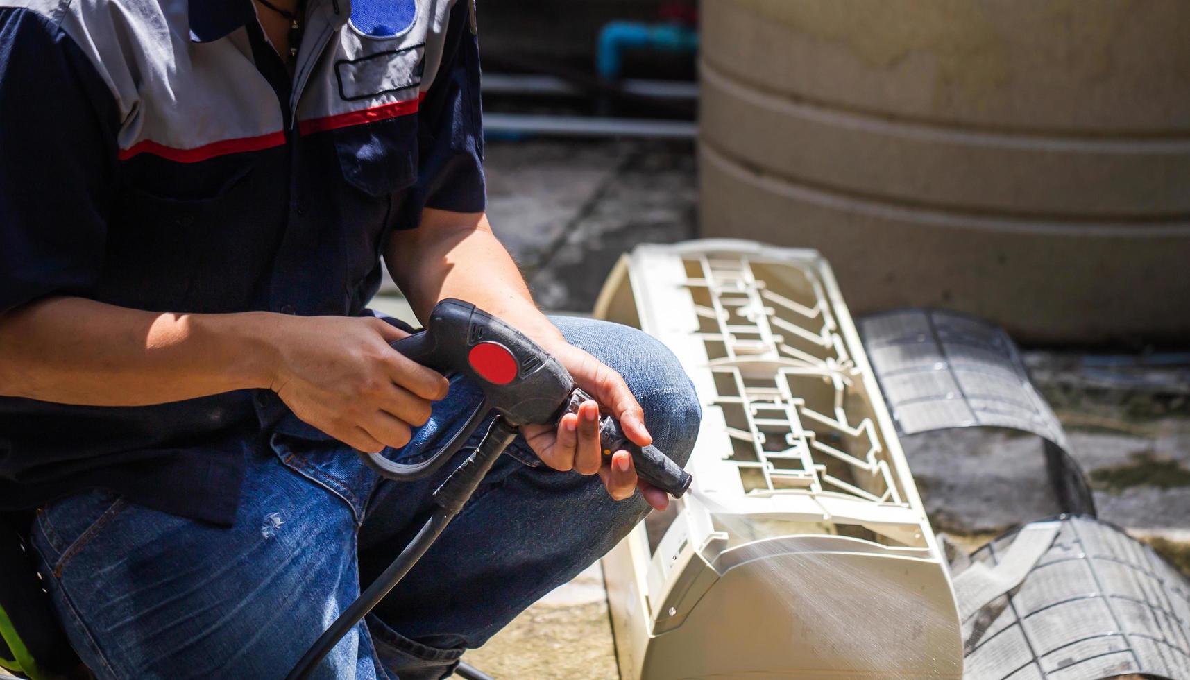 mannelijke technicus die airconditioner binnenshuis schoonmaakt, reparateur die vuile compartimenten wast airconditioner, onderhouds- en reparatieconcepten foto