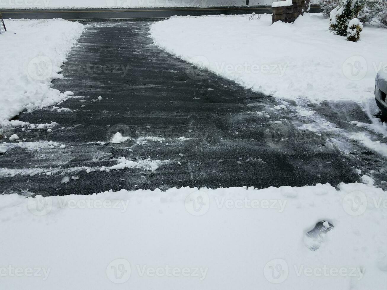 asfalt oprit met witte sneeuw schuiven in de winter foto