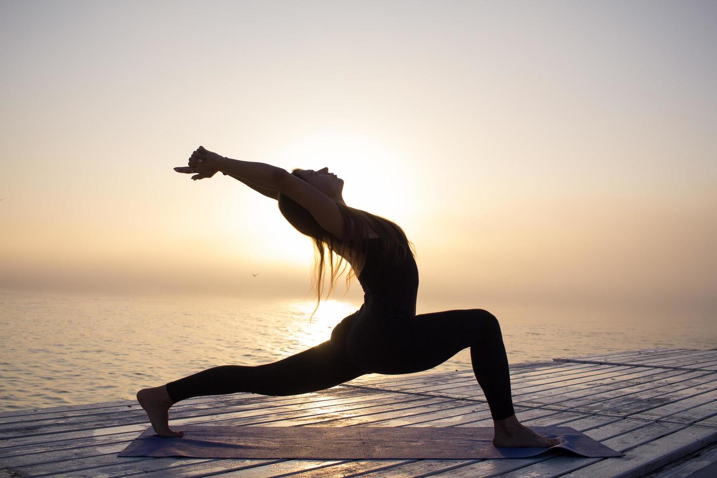 jonge vrouw poseren in yoga asans, ochtend zee achtergrond foto