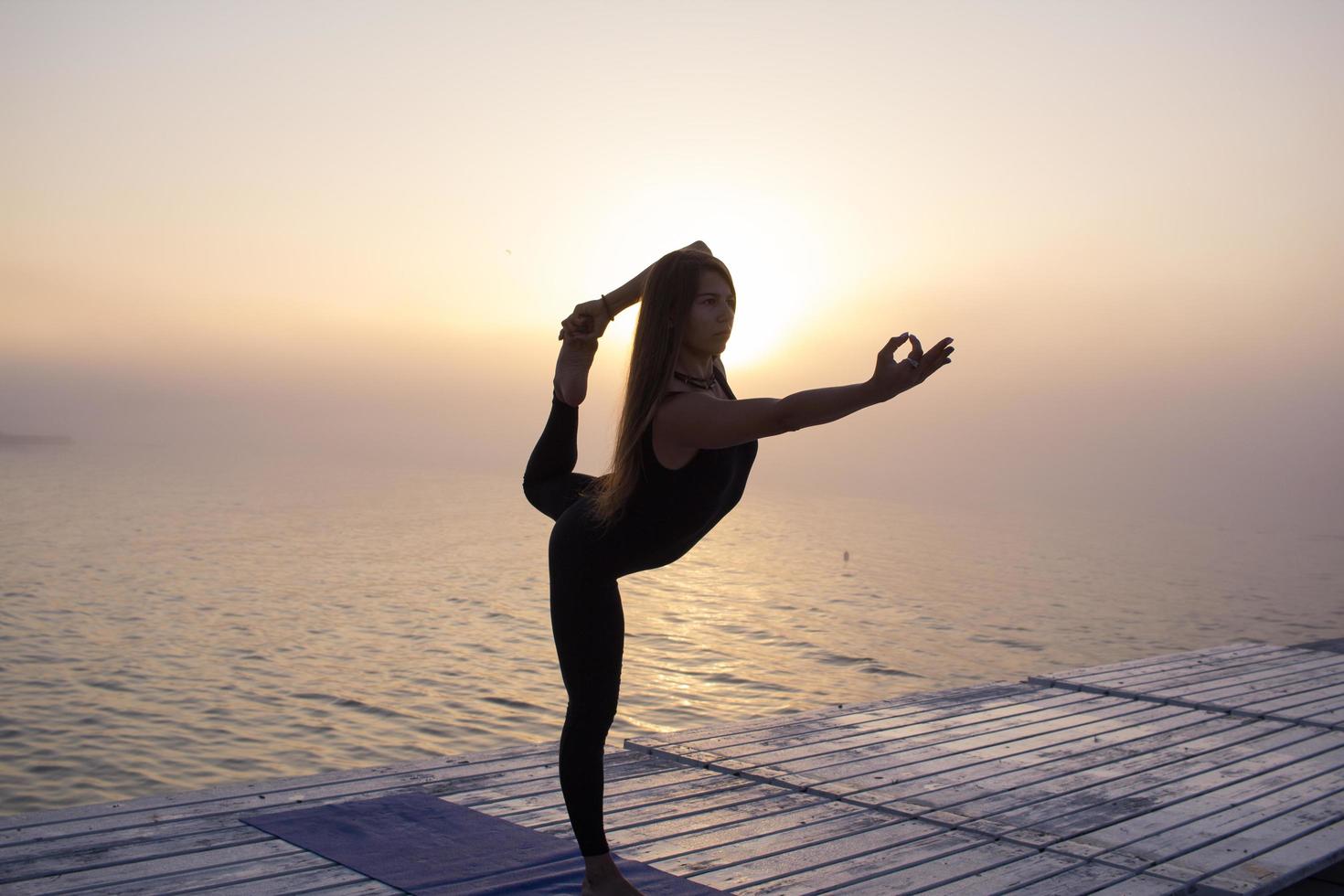 jonge vrouw poseren in yoga asans, ochtend zee achtergrond foto