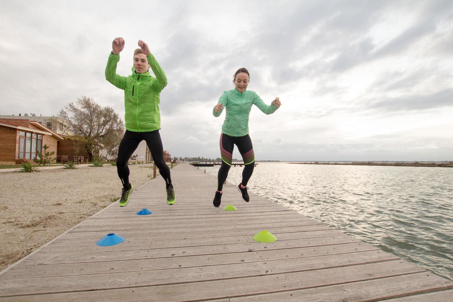 groep jongeren die buiten traint, hardlopersoefeningen, zee- of rivierachtergrond foto