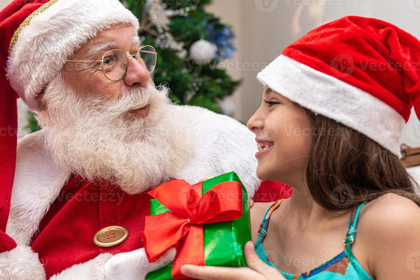 de kerstman levert een geschenkdoos aan een klein meisje. kerstavond, levering van geschenken. foto