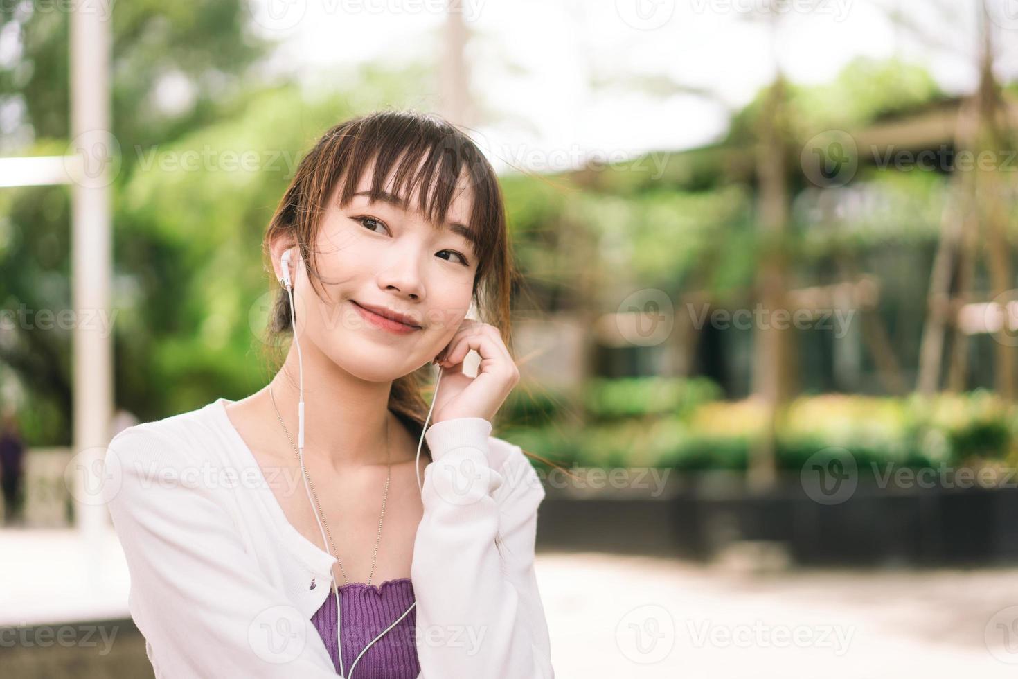 gelukkige jonge volwassen aziatische vrouw die op dag streaming muziek luistert in de buitenlucht. foto