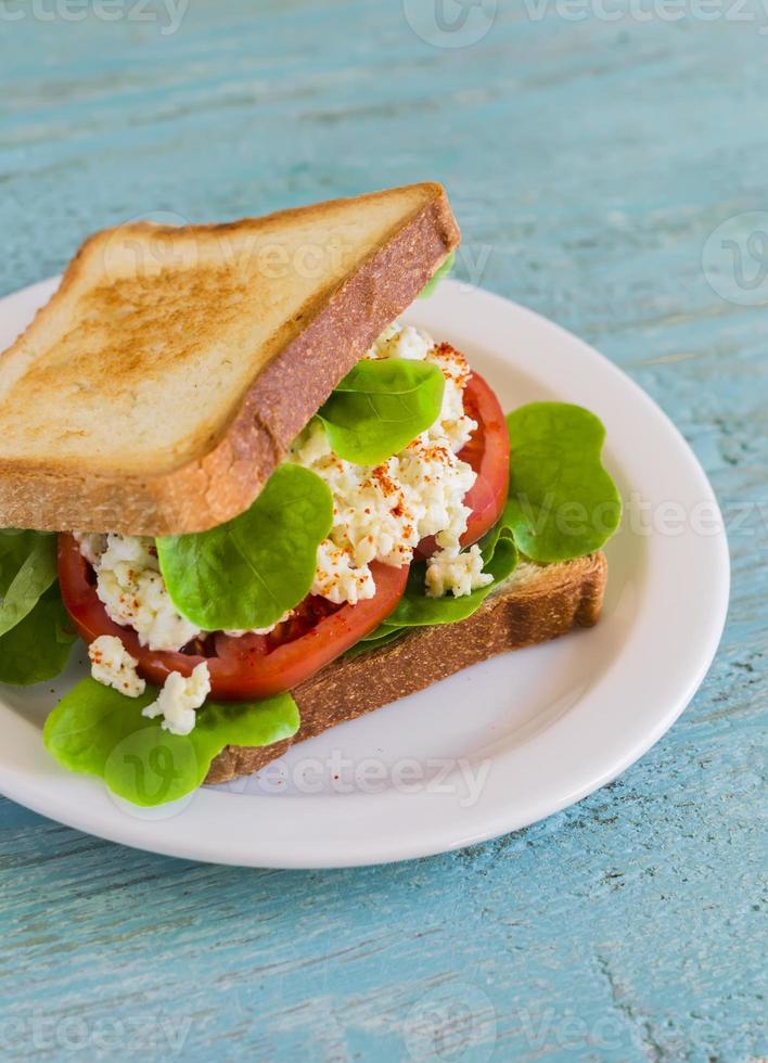 sandwich met ei, tomaat en sla op een witte plaat foto