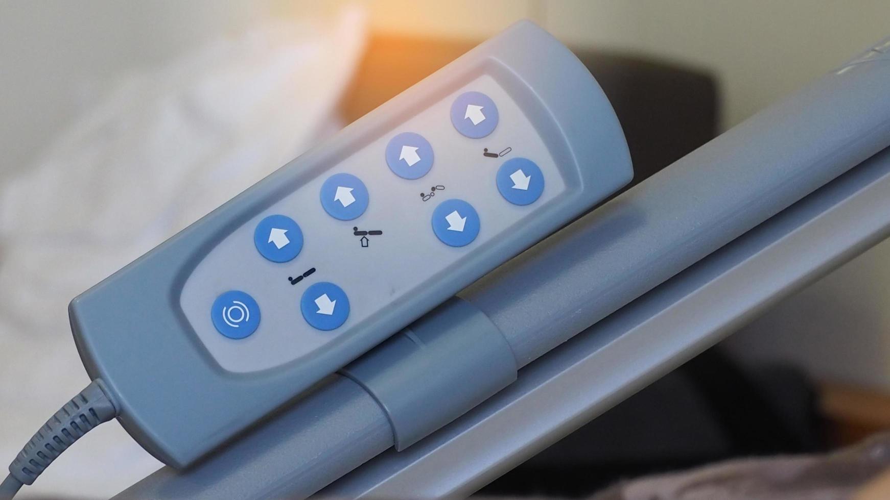 close-up afstandsbedieningspaneel van elektrisch verstelbaar bedgebruik om het bed van de patiënt comfortabel aan te passen. verstelbaar ziekenhuisbed. afstandsbediening met 8 blauwe knop. elektrisch ziekenhuisbed voor gehandicapte. foto