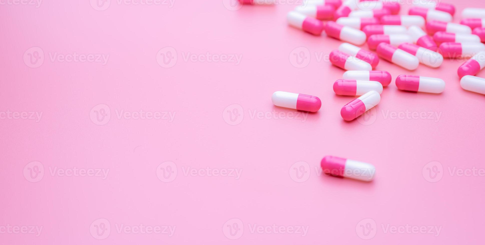roze-witte antibioticum capsules pil verspreid op roze achtergrond. antibioticum resistentie concept. slim gebruik van antibiotica. antimicrobieel medicijn. gezondheidsbudget en beleid. farmaceutische industrie. foto