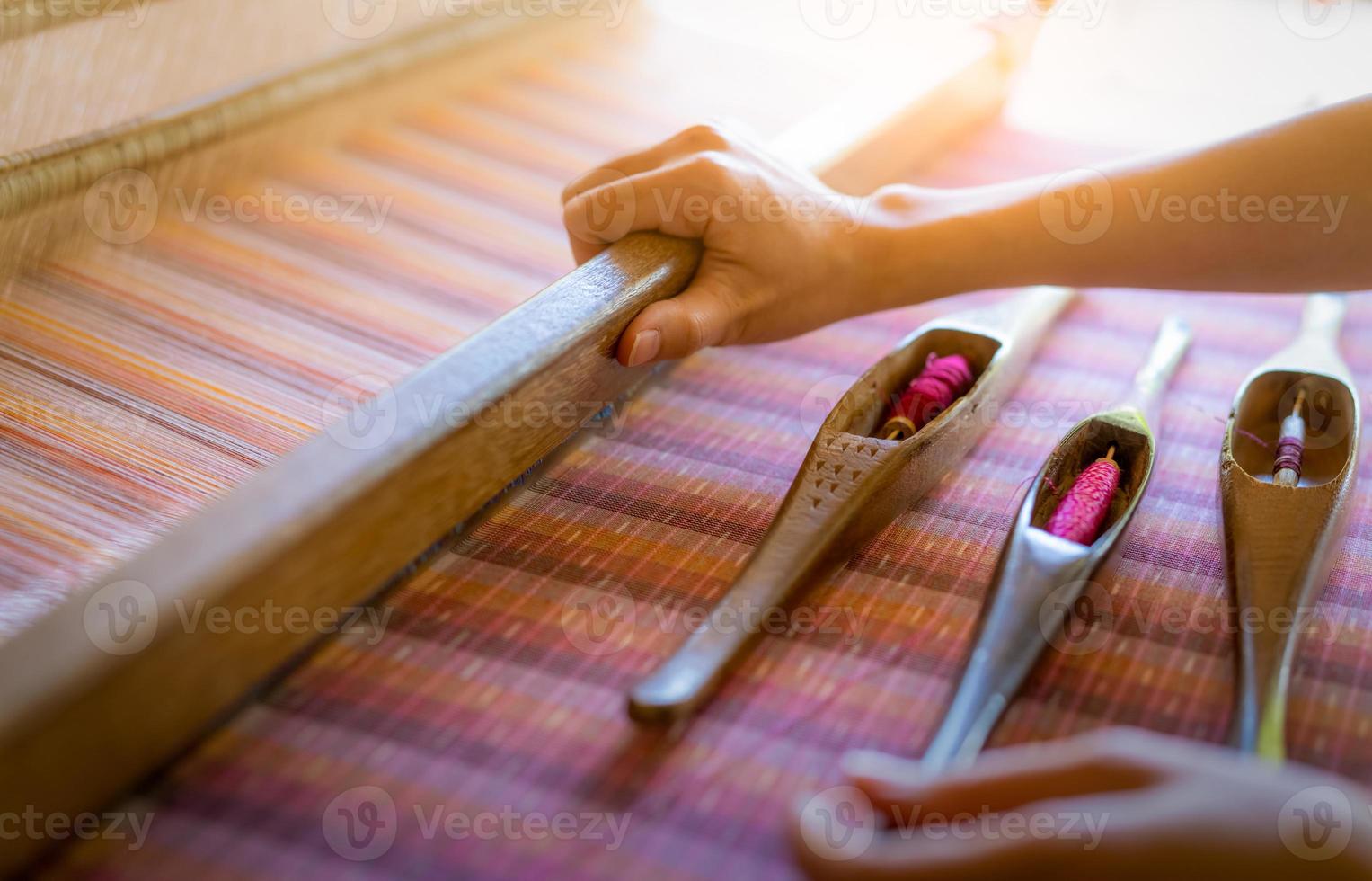 vrouw die werkt aan een weefmachine voor het weven van handgemaakte stof. textiel weven. weven met behulp van traditioneel handweefgetouw op katoenen strengen. textiel- of stoffenproductie in thailand. Aziatische cultuur. foto