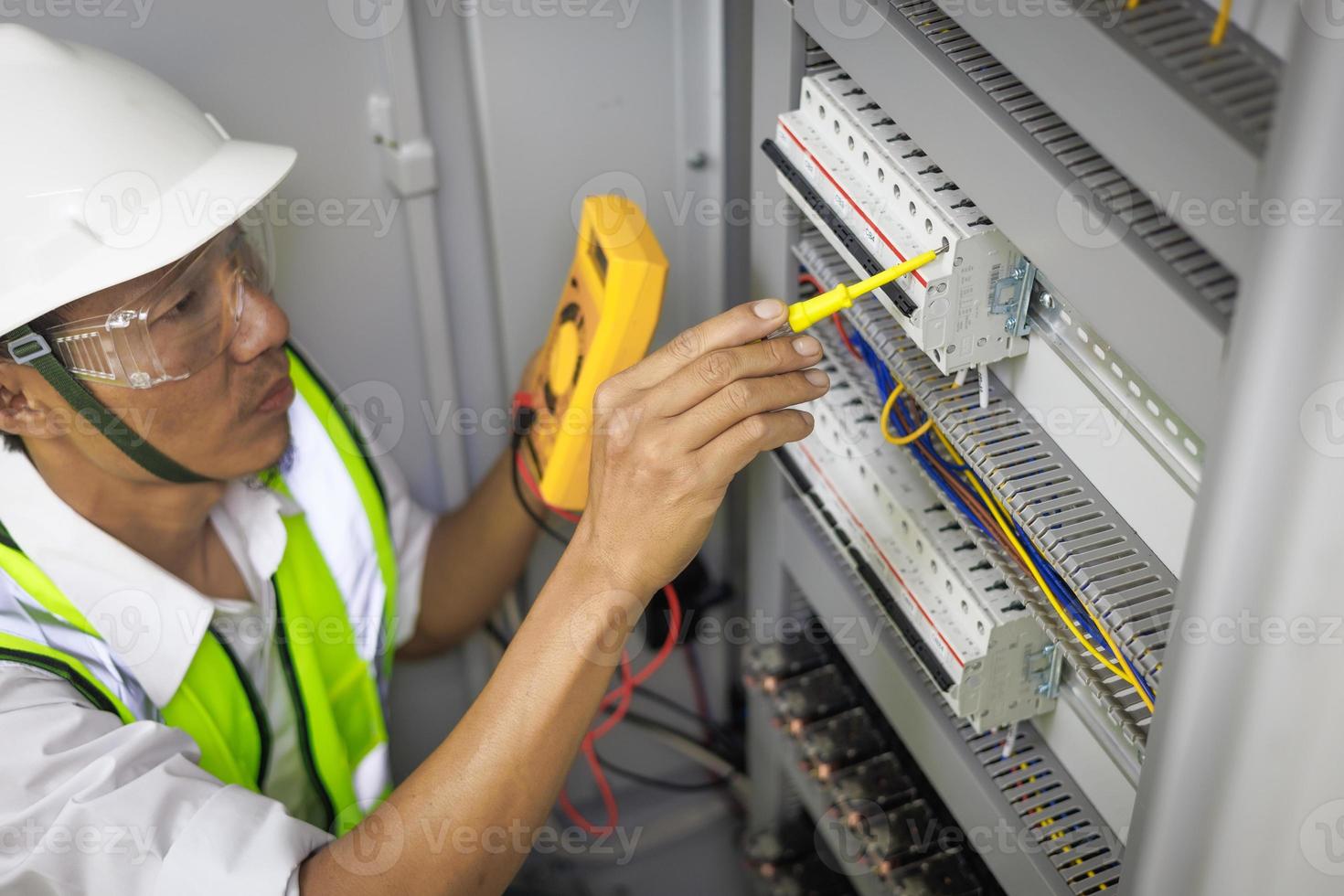 een mannelijke elektricien werkt in een bedieningspaneel met elektrische verbindingen die apparaten verbinden met een complexe werkconcepttool. foto