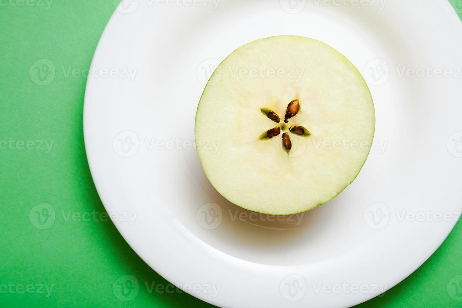 witte plaat met een halve appel op groene achtergrond. foto