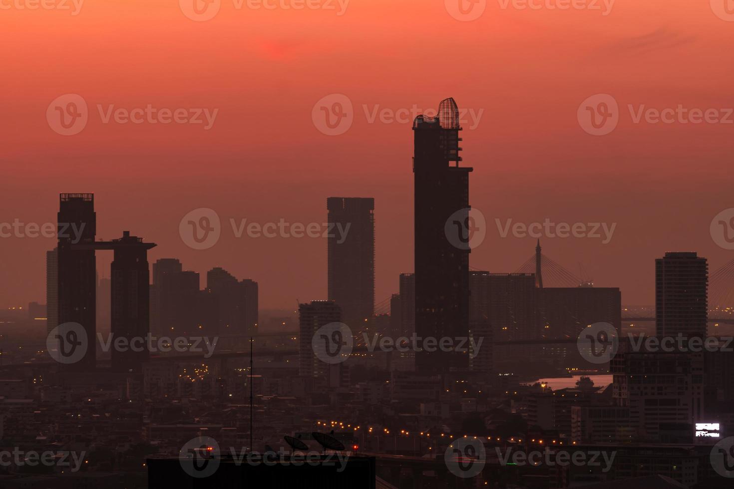 stadsgezicht in de ochtend met rode zonsopganghemel. stad bedekt met smog. luchtvervuiling probleem. wolkenkrabber gebouw in het centrum. stedelijke horizon. silhouet moderne kantoor- en hotelgebouw in de stad bij dageraad. foto