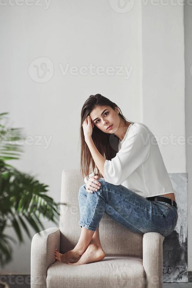 vrouw op blote voeten. jonge brunette in de kamer met witte muren en daglicht dat uit het raam komt foto