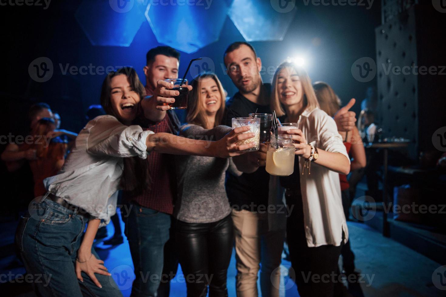 word gek. groep jonge vrienden die glimlachen en een toast uitbrengen in de nachtclub foto