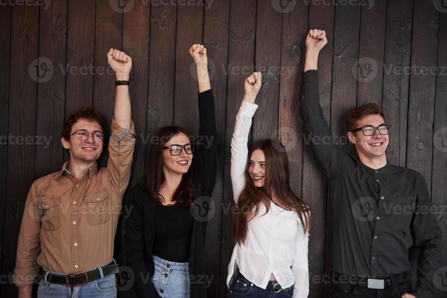 binding van mensen. succes vieren. vrienden steken hun handen tegen een zwarte houten muur foto